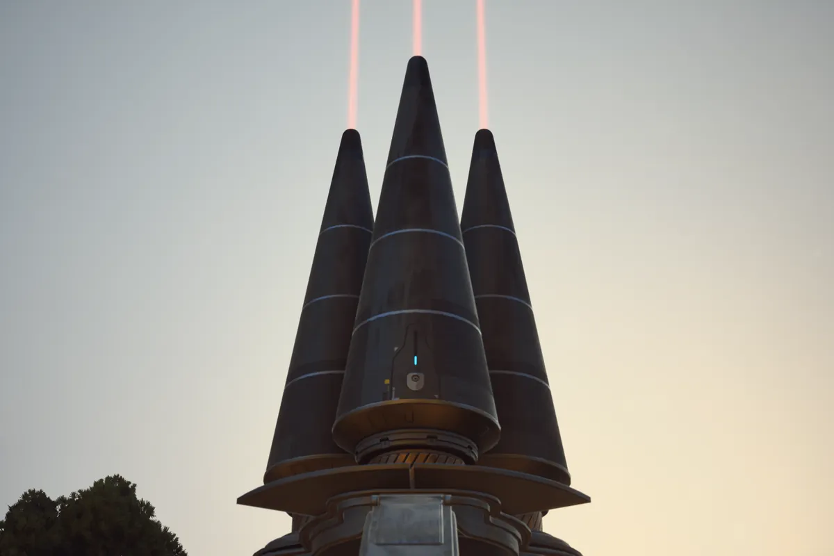 夕方の空に、黒い円すいを 3 本束ねた ARC アセッサーが立ち、先から赤い光が空へ伸びている