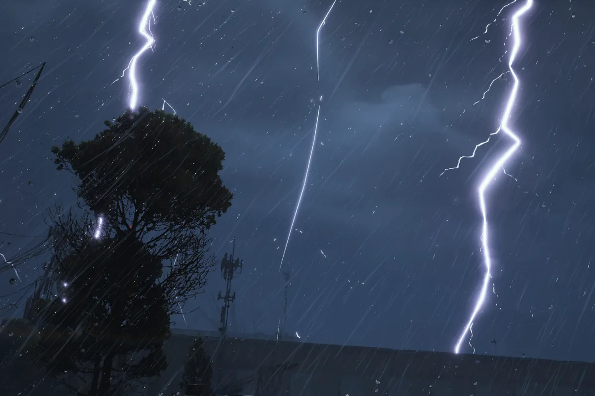 雨の夜空に何本もの稲妻が走り、木と鉄塔の影の向こうに雷が落ちている
